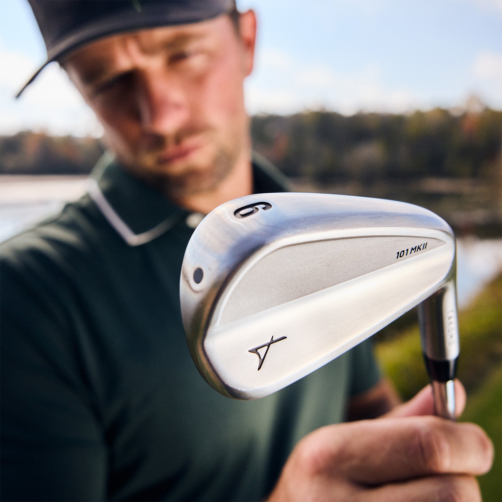 Man holding a golf club with a blurred natural background