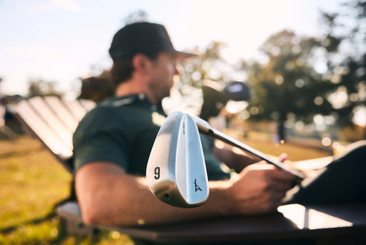Golfer holding a silver iron close to the camera on a golf course