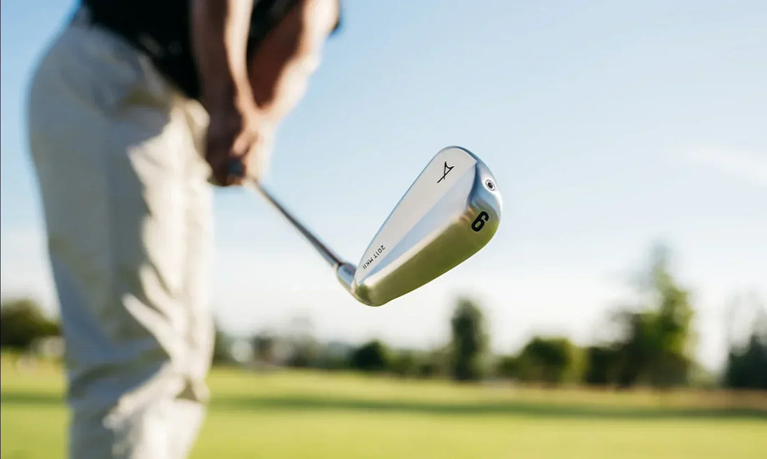Close-up of a golfer holding a silver 6-iron over a golf course