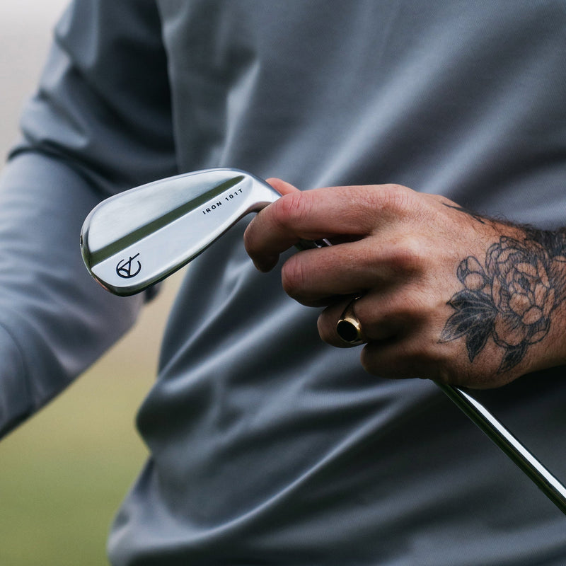 Golf player holding an iron with Takomo branding.