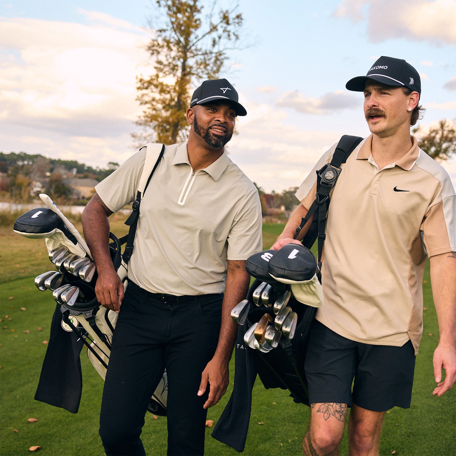 Two men walking on a golf course with golf bags.