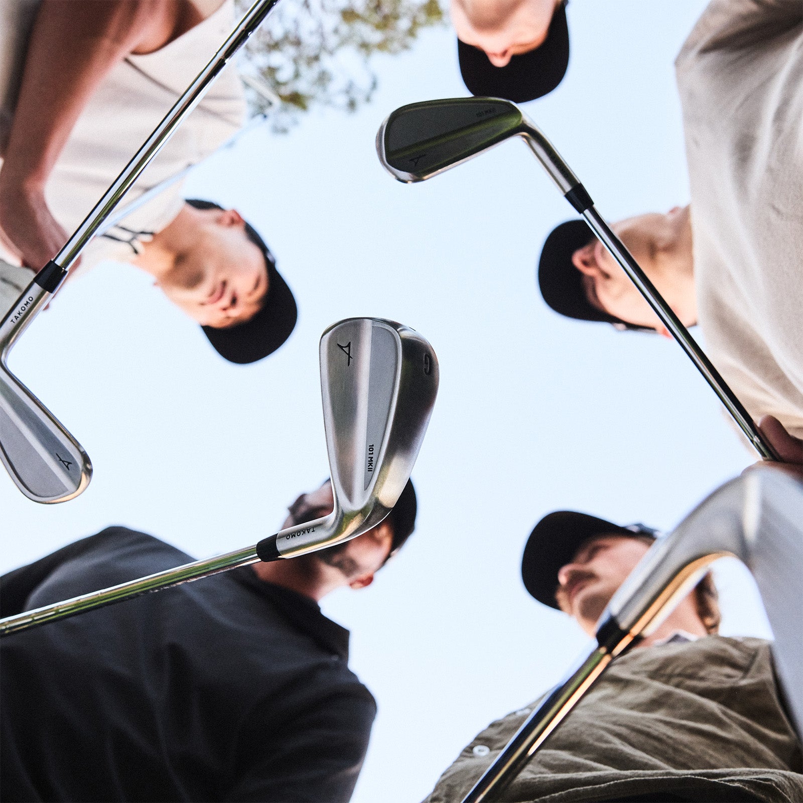 Multiple golfers holding golf clubs with a clear sky background