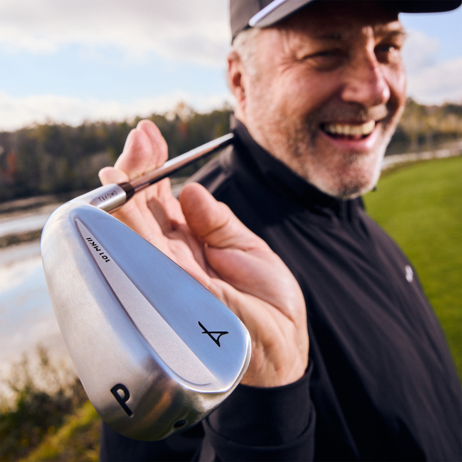 Man holding a golf club with a scenic background