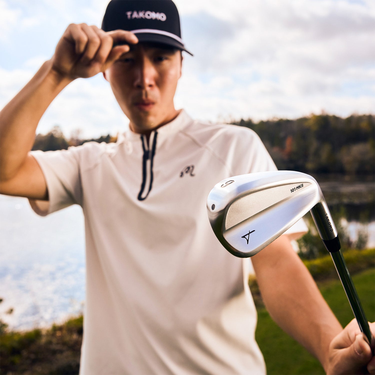 Person holding a golf club with a blurred natural background