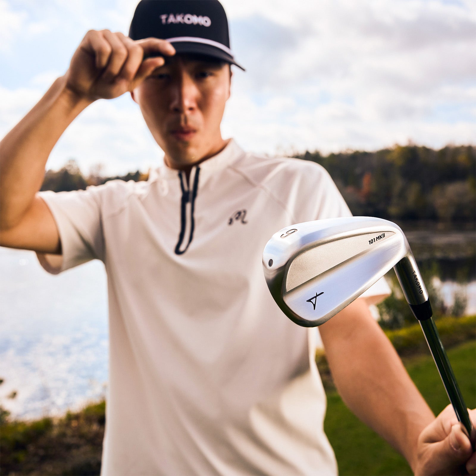 Person holding a golf club with a blurred natural background