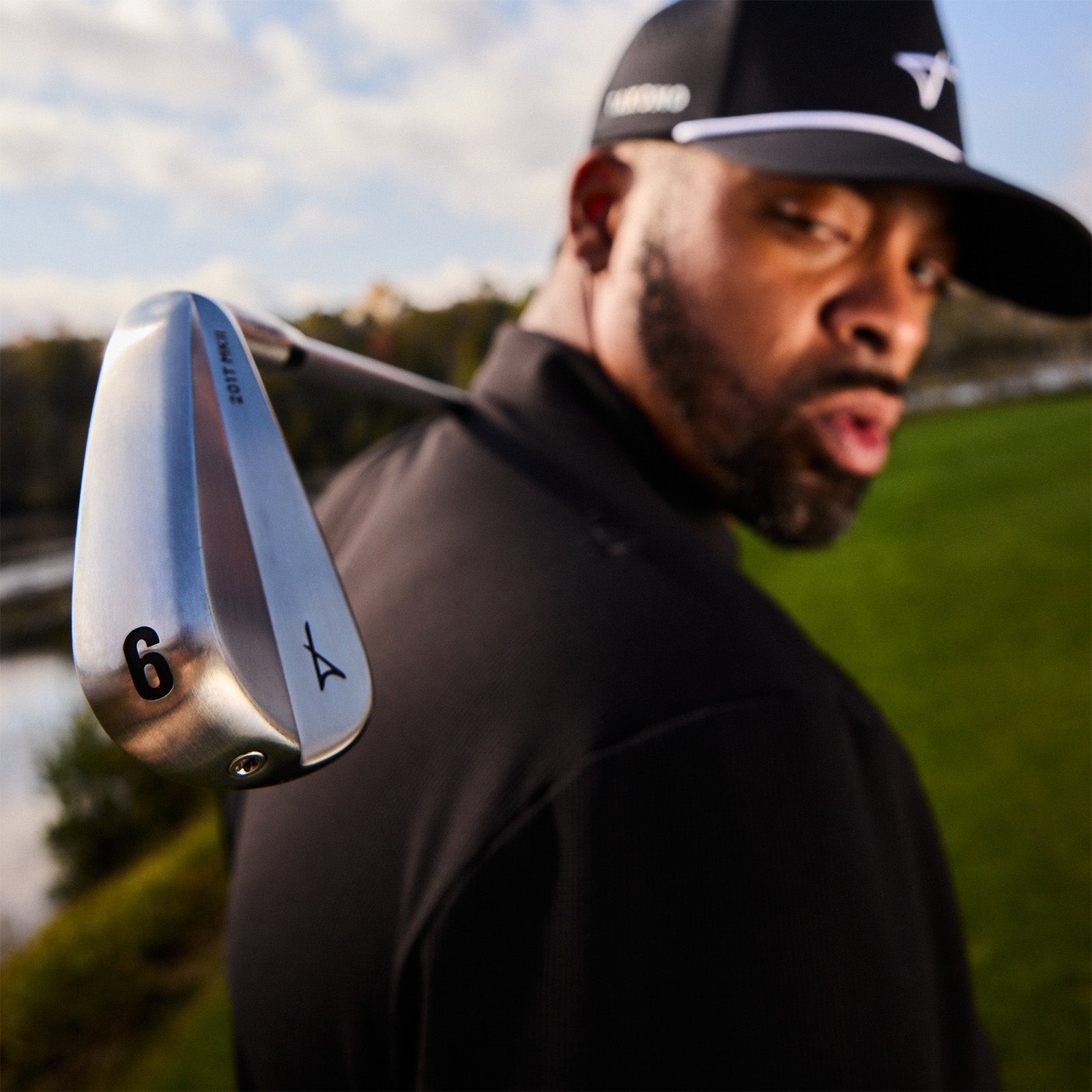 Man holding a golf club on a golf course with a blurred background