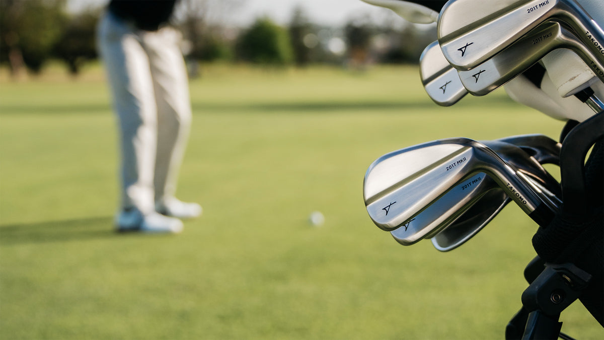 Close-up of golf clubs with a blurred golf course background