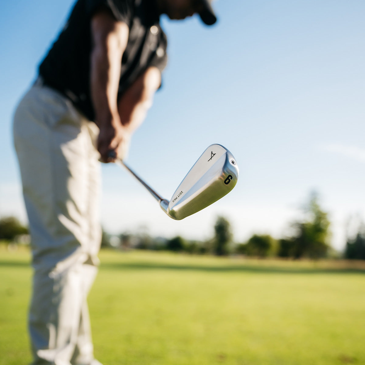 Golf club with Takomo logo held by a golfer on a golf course