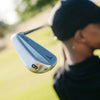 Close-up of a golf club head with a blurred person in the background