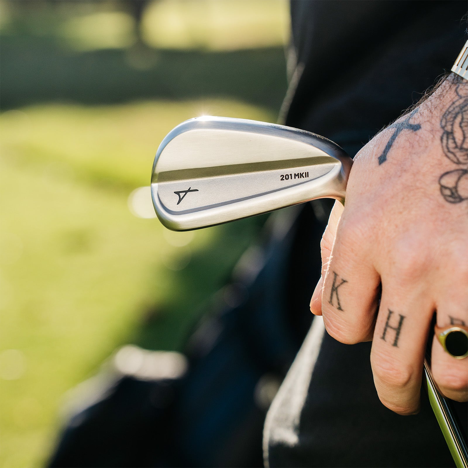 Close-up of a hand holding a golf club with a blurred golf course background