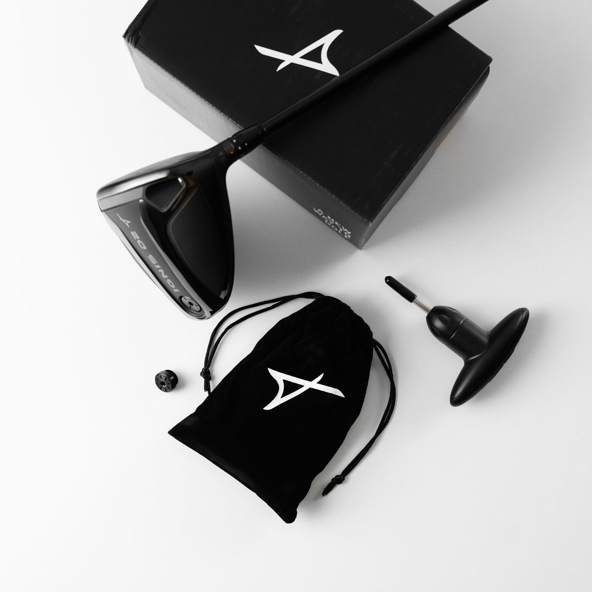 A black Takomo IGNIS D2 driver head with related accessories laid neatly on a white background.