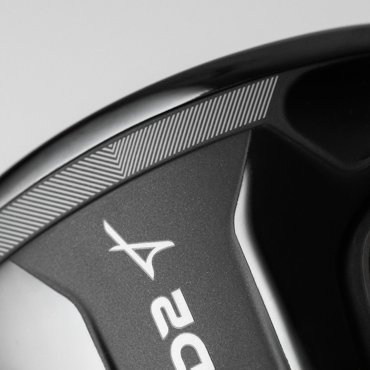Close-up of a black golf club head showing the Takomo logo and part of the 'D2' model number, with line detailing in focus.