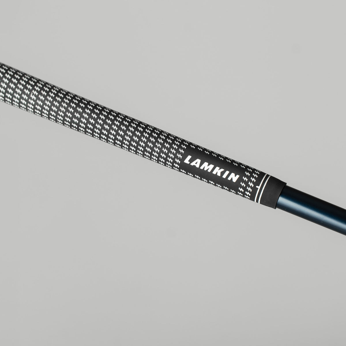 Close-up of a black and white Lamkin Crossline grip on a golf club shaft.