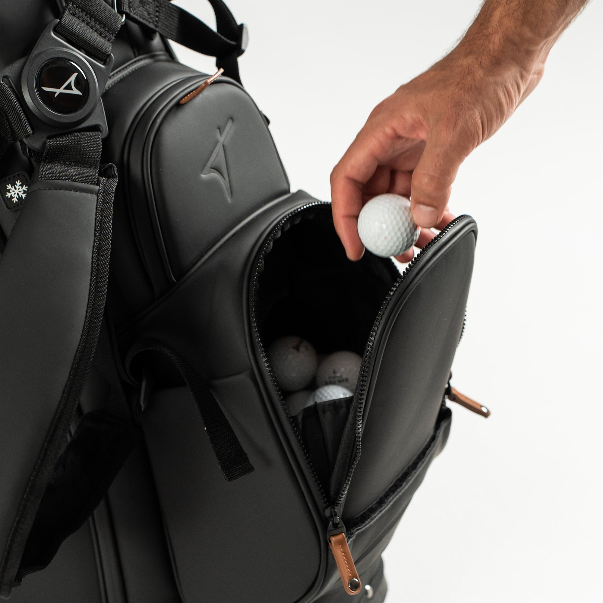 Person placing a golf ball into a golf bag on a white background