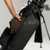 Black golf bag with golf clubs and a brown cloth on a gray background