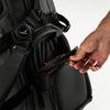 Person opening a black golf bag pocket with a white background
