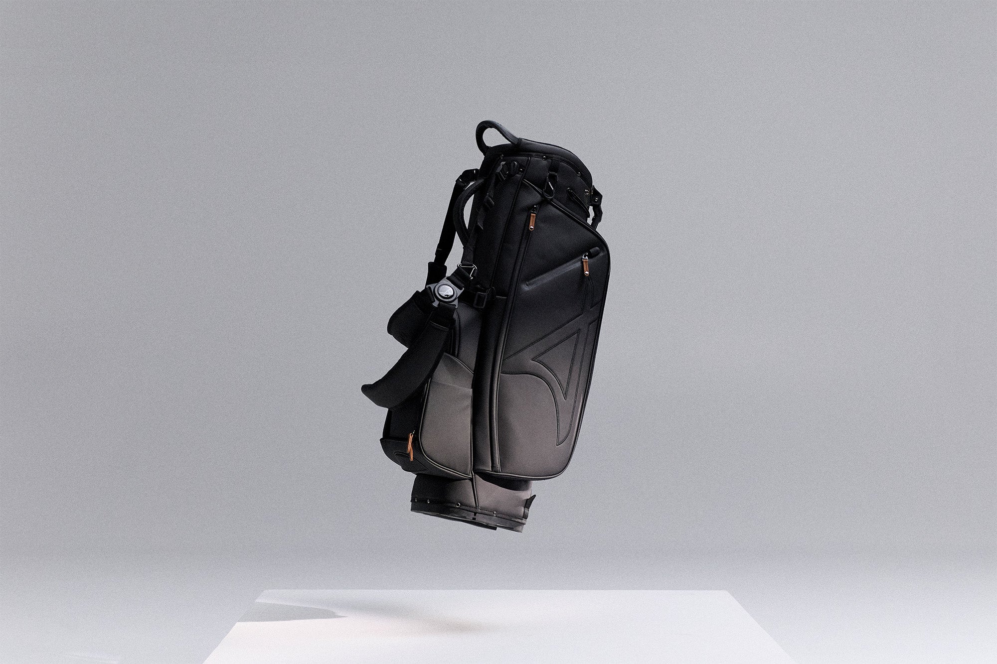 Black golf bag on a white pedestal against a light gray background