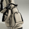 White golf bag with black straps on a light gray background