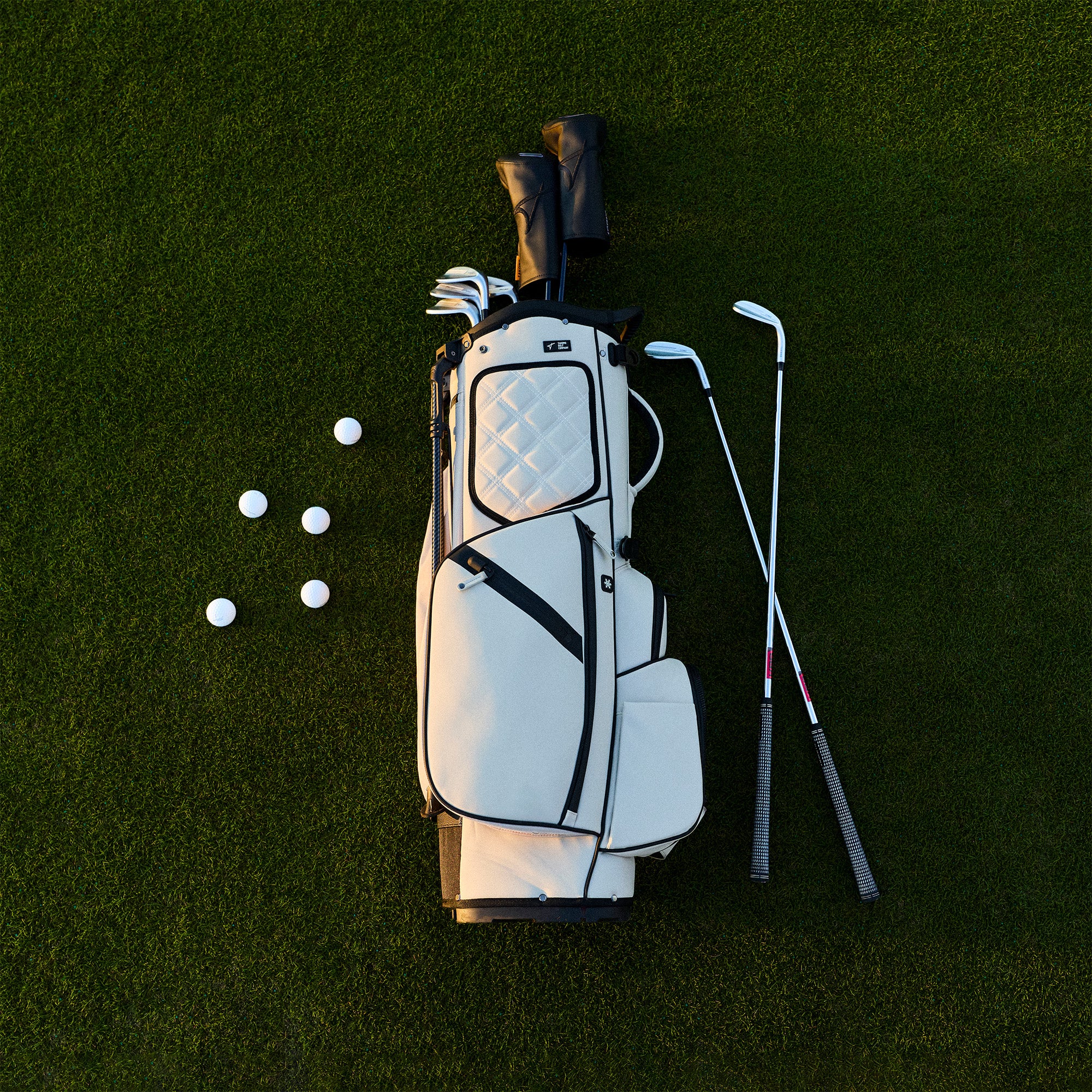 Golf bag with clubs and balls on a green grass background