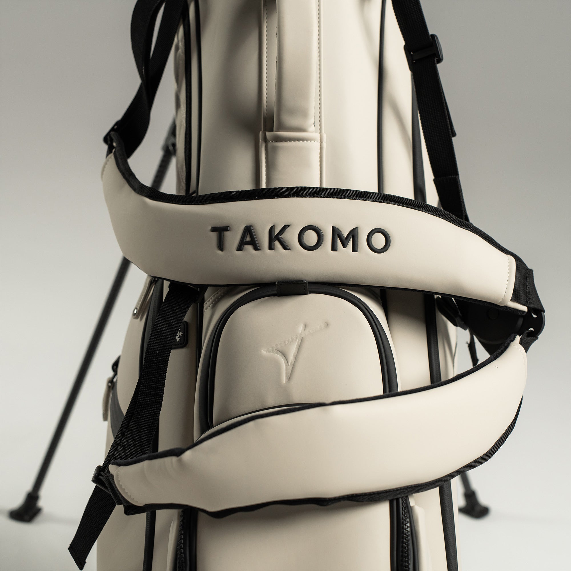 White golf bag with black straps and 'Takomo' branding on a light gray background