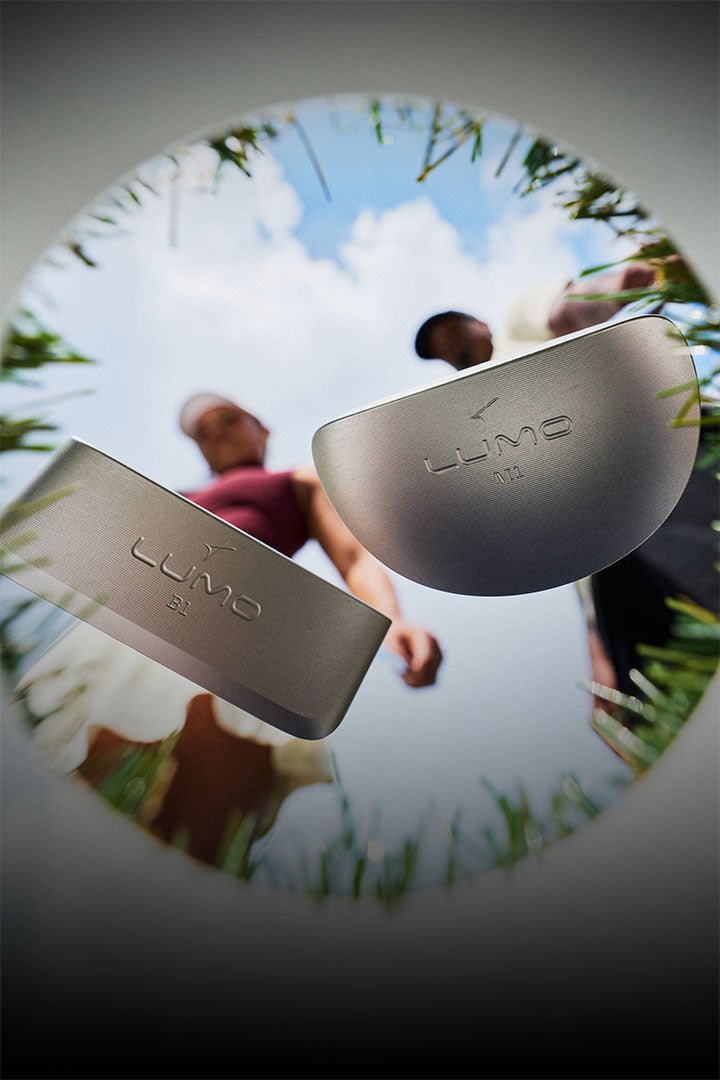 Two Takomo Lumo putters hovering above a golf hole, captured from below.